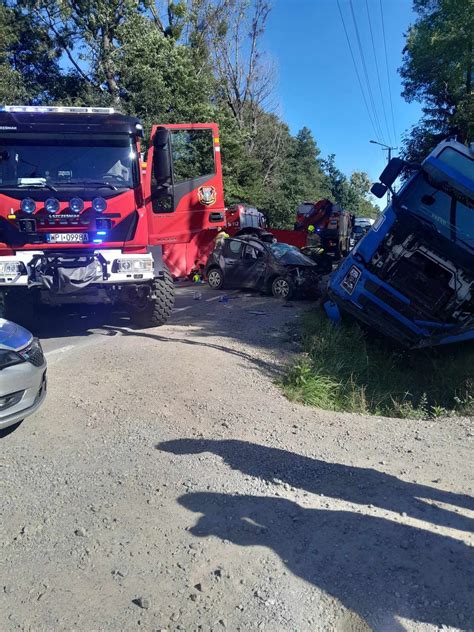 Scena wypadku z przewróconym TIR-em i uszkodzonymi ciężarówkami na drodze krajowej