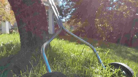 Thematic photo of a person mowing a small, perfectly manicured lawn with a manual reel mower