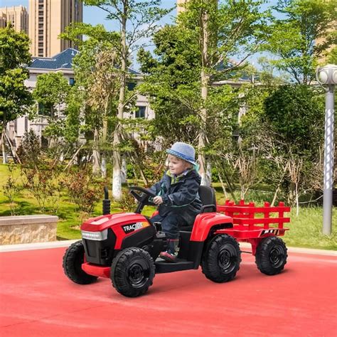 Thematic photo of a child riding an electric tractor with a trailer in a garden setting.