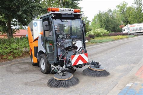 Zamiatarka uliczna w pracy, zbierająca zanieczyszczenia z asfaltowej drogi