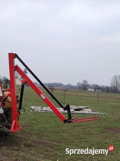 Zdjęcie ładowacza hydraulicznego do bel z samopoziomem, zamontowanego na tyle ciągnika, w trakcie pracy