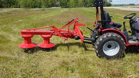 Thematic photo of a rotary drum mower with drive in action, cutting tall grass on an uneven field