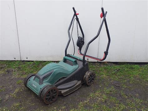 Thematyczne zdjęcie przedstawiające różne typy kosiarek Parkside (spalinową, elektryczną, akumulatorową) na tle zadbanego ogrodu.