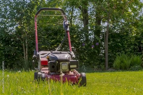 Tematyczne zdjęcie traktorka kosiarki pracującego na rozległym trawniku