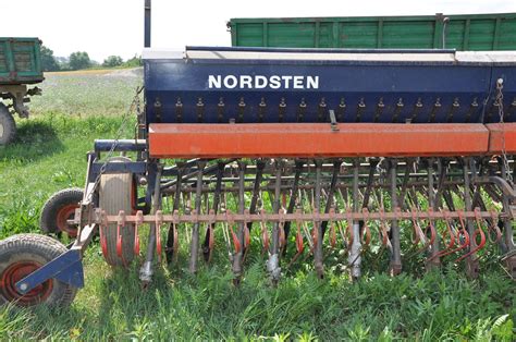 zdjęcie porównawcze dwóch siewników Nordsten, jeden z czerwoną klapą, drugi starszego typu