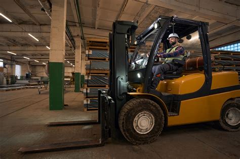 Zdjęcie operatora wózka widłowego w odpowiednim stroju ochronnym, sprawdzającego stan techniczny pojazdu