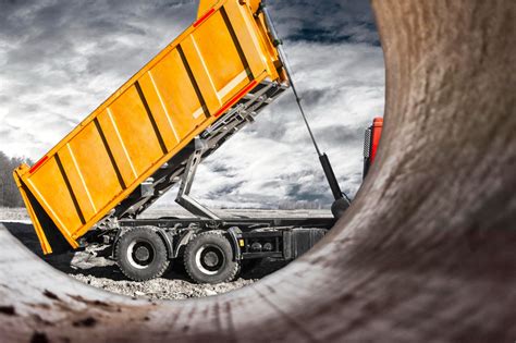 Ilustracja przedstawiająca różne rodzaje materiałów sypkich, które można przewozić wywrotką (np. piasek, żwir, węgiel).