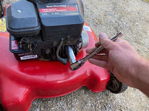 Thematic photo of a person checking a spark plug on a lawn mower