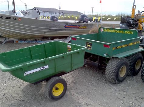 Thematic photo of a John Deere ATV with a dump trailer attached, working in a garden or light construction setting.