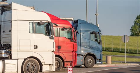 Zdjęcie przedstawiające kierowcę ciężarówki na parkingu, w oddali inne ciężarówki