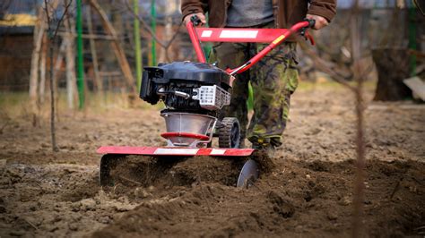 Thematic photo of a person operating a rotavator in a garden