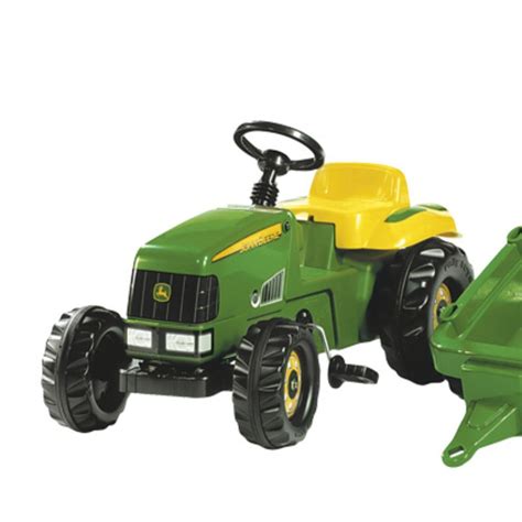 Zdjęcie przedstawiające dziecko bawiące się traktorkiem John Deere na pedały z przyczepką na zewnątrz