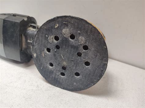 Zdjęcie przedstawiające zawartość zestawu szlifierki mimośrodowej JCB: szlifierka, akumulator, ładowarka, woreczek na pył, tarcze ścierne, torba.