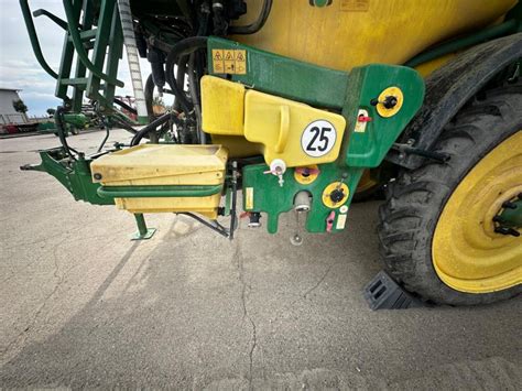 Zdjęcie panelu sterowania opryskiwacza John Deere 832 z opisem funkcji przycisków i wskaźników