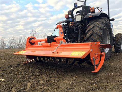 Thematic photo of a rotary tiller attached to a tractor working in a field