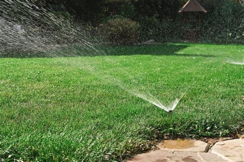 Photo of a lawn being watered by a sprinkler system
