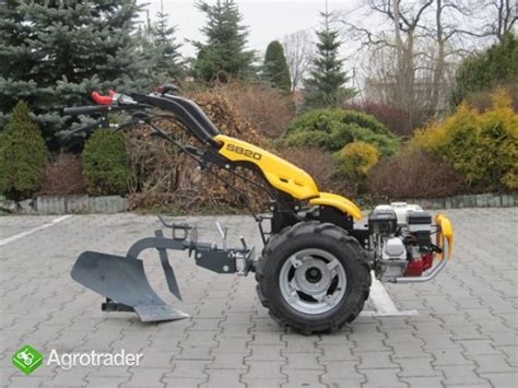 Traktorek jednoosiowy z zamontowanym pługiem do orki i kołami metalowymi