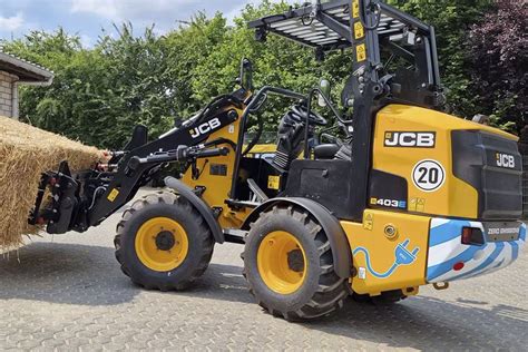 The JCB 403E electric wheel loader working in an agricultural setting, showcasing its compact size and modern design.