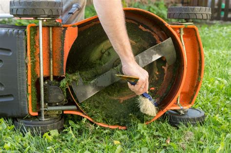 Photo of a person cleaning a lawnmower after use