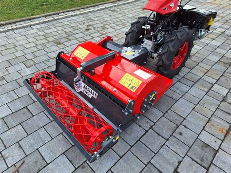 Zdjęcie ciągnika jednoosiowego z doczepioną glebogryzarką w akcji na polu uprawnym