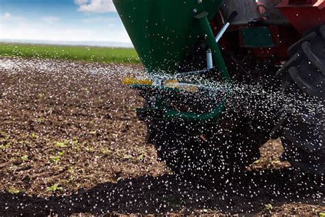 The Iseki box spreader in action on a field, spreading seeds or fertilizer.