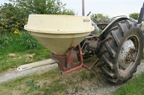 A photo of an Iseki centrifugal spreader attached to a tractor.