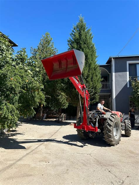 Thematic photo of a tractor with a rear loader in operation, e.g., loading hay or manure.
