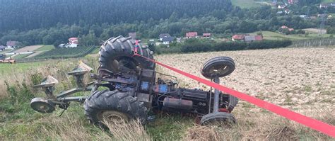 Zdjęcie przedstawiające przewrócony ciągnik rolniczy na polu lub scenę działań ratowniczych