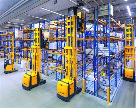 Zdjęcie przedstawiające nowoczesny magazyn wysokiego składowania z operatorem obsługującym wózek widłowy.