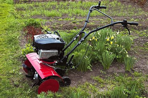 Thematic photo of a person operating a rototiller in a garden, with Marki as a blurred background element if possible