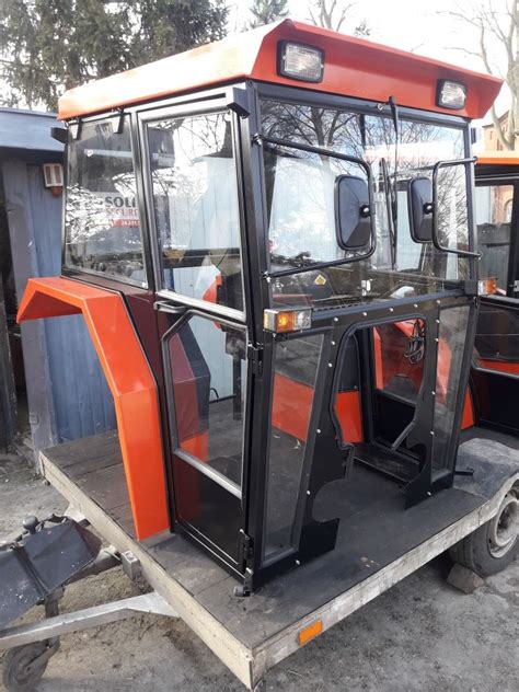 Ilustracja kabiny ciągnika Belarus z zaznaczonymi elementami ergonomicznymi i systemem ROPS/FOPS