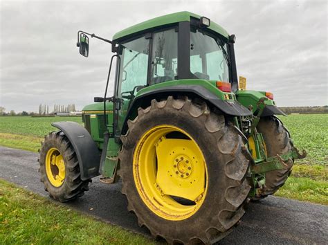 Widok z boku ciągnika John Deere 6100 D pracującego w polu