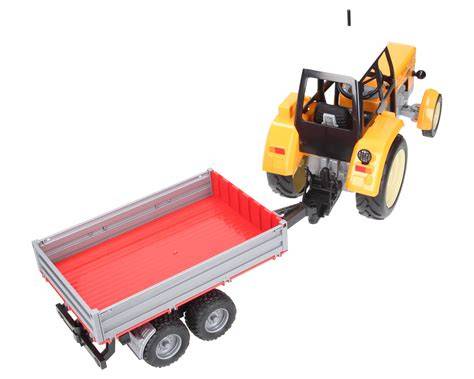 Żółty traktor zabawkowy z przyczepą, wykonany z plastiku, z widocznymi gumowymi kołami i mechanizmem skrętnym