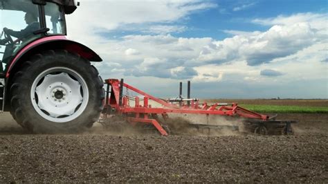 Ciągnik rolniczy z podłączonym dużym agregatem uprawowym podczas pracy w polu