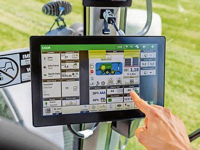 Operator w kabinie ładowarki John Deere z ekranem dotykowym