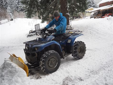 Thematic photo of a quad with a snow plow actively clearing snow
