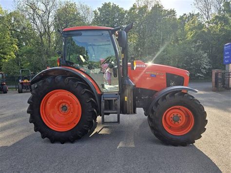 Zdjęcie ciągnika Kubota M115GX IV pracującego w polu z agregatem uprawowym