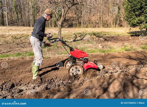 Thematic photo of a person working in a garden with a soil tilling machine