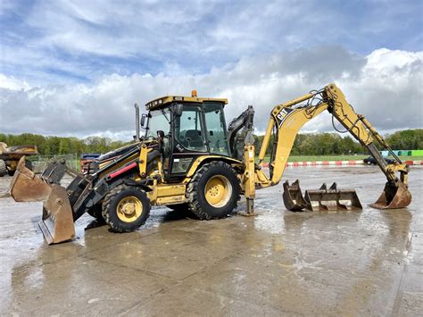 Schemat przedstawiający koparko-ładowarkę Caterpillar 432D w akcji na placu budowy.