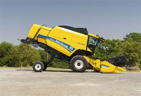 New Holland TC4.90 combine harvester harvesting grain in a small to medium-sized field, emphasizing its compact design.