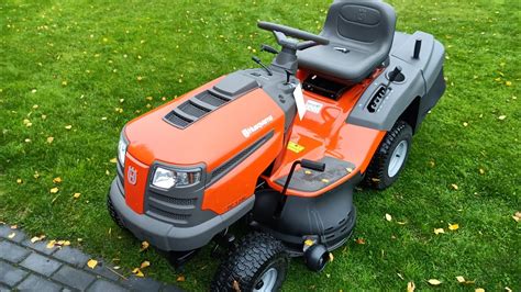 Ilustracja przedstawiająca ergonomiczną pozycję operatora na traktorku Husqvarna z widocznymi pedałami i dźwigniami