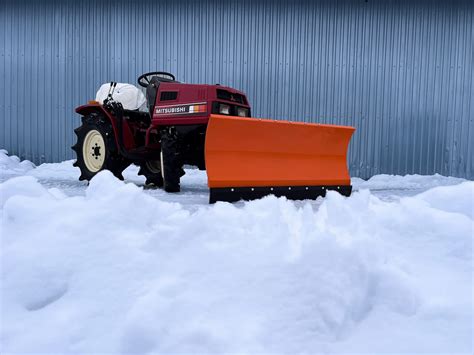zdjęcie małego ciągnika 4x4 w akcji, np. odśnieżającego drogę