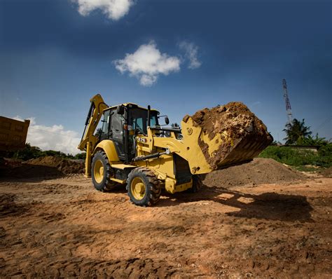 Thematic photo of a CAT backhoe loader with a hydraulic grading bucket attached, working on a slope.
