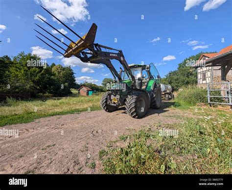 Thematic photo of a used front loader attached to a tractor in a rural setting