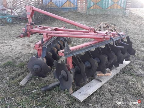 Zdjęcie przedstawiające bronę talerzową w trakcie pracy na polu, mieszającą resztki pożniwne