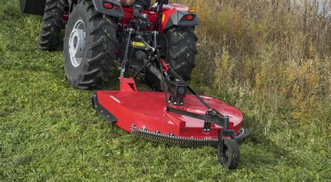 Thematic photo of a small tractor with a rotary mower in action on a field
