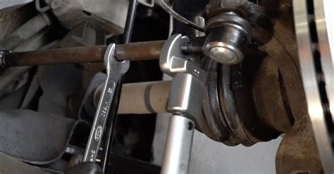 Zdjęcie przedstawiające mechanika wymieniającego końcówkę drążka kierowniczego