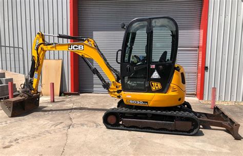 The JCB 8030 ZTS miniexcavator in action, demonstrating its zero tail swing capability in a tight urban construction site.