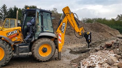 koparka JCB z zamontowanym młotem hydraulicznym podczas pracy