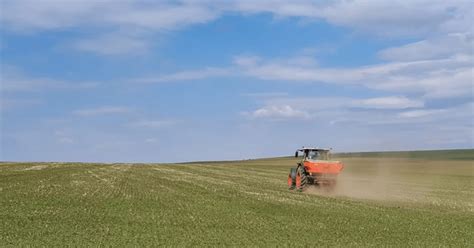 Thematic photo of a KOS fertilizer spreader working in a field during spring